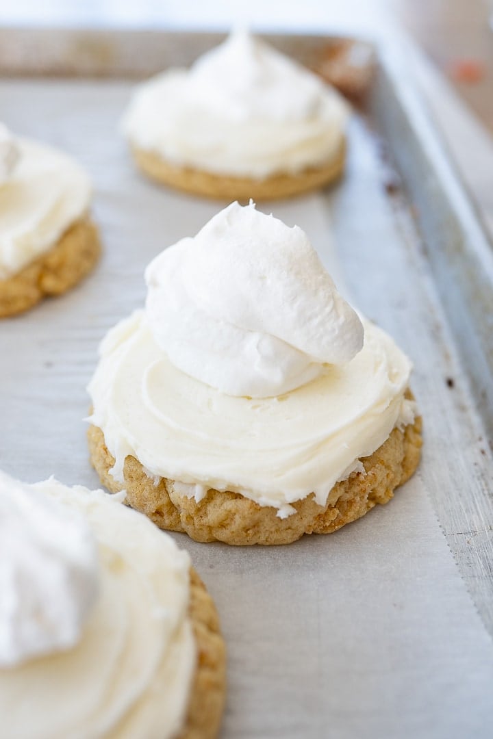 Cookies frosting with coconut buttercream and a dollop of whipped cream on top of each cookie.