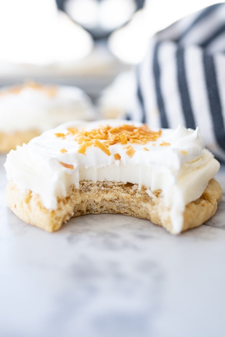 A side view of a coconut cream pie cookie with a bite taken out of it.