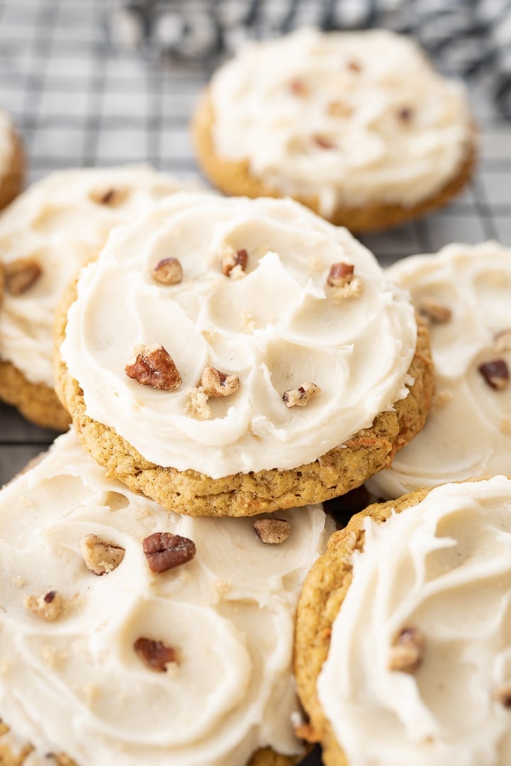 Up close photo of carrot cake oatmeal cookies topped with cream cheese frosting and chopped pecans.