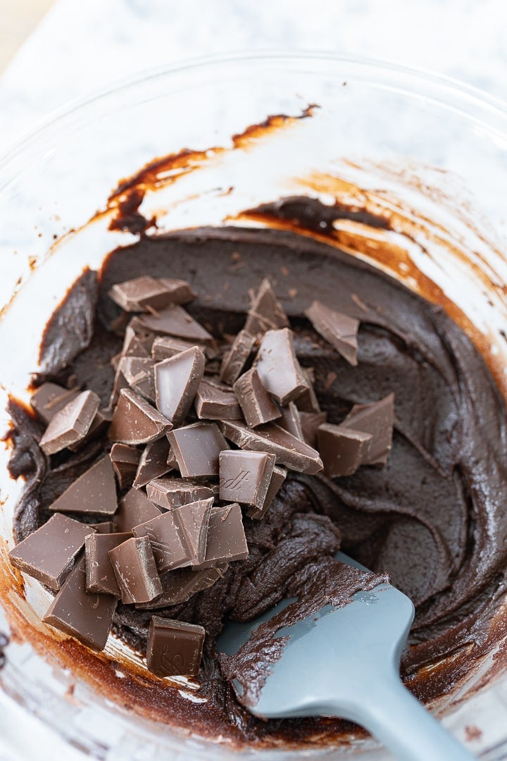 Brownie batter in a bowl with chunks of chocolate on top of the batter.
