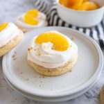 peaches and cream cookie on a plate next to peach halves.