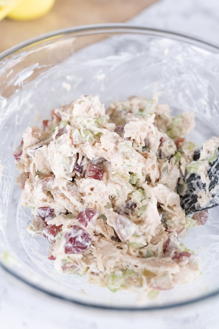 Chicken salad mixed up in a large glass bowl, ready to be put in croissants. 