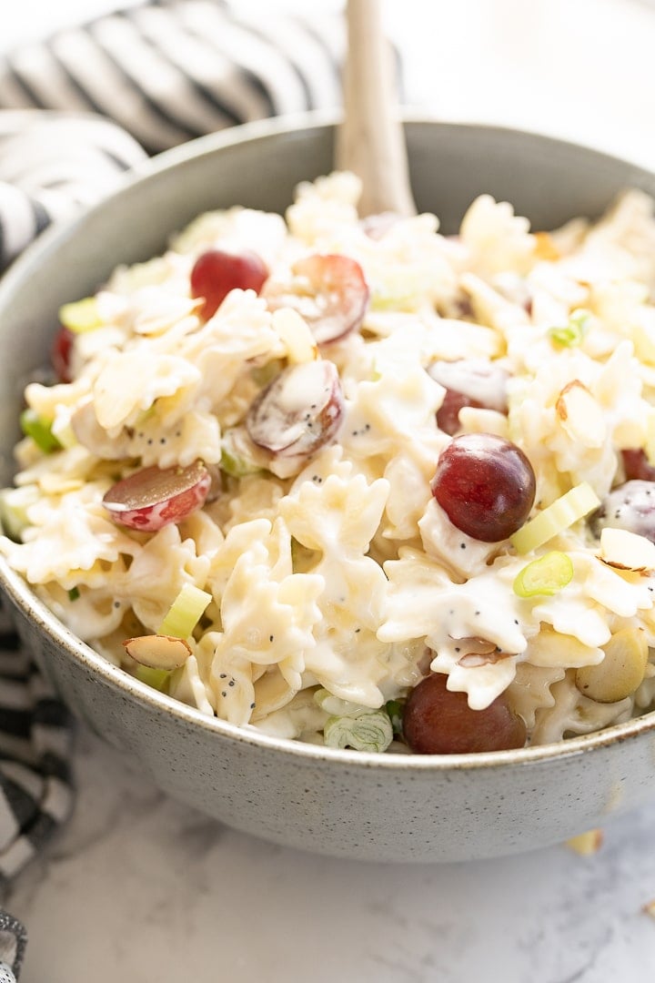 Side view of chicken pasta salad in a bowl with a spoon coming out of it. 