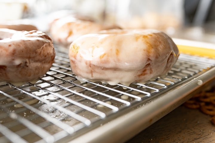 Side view of freshly glazed donuts on a wire rack. 