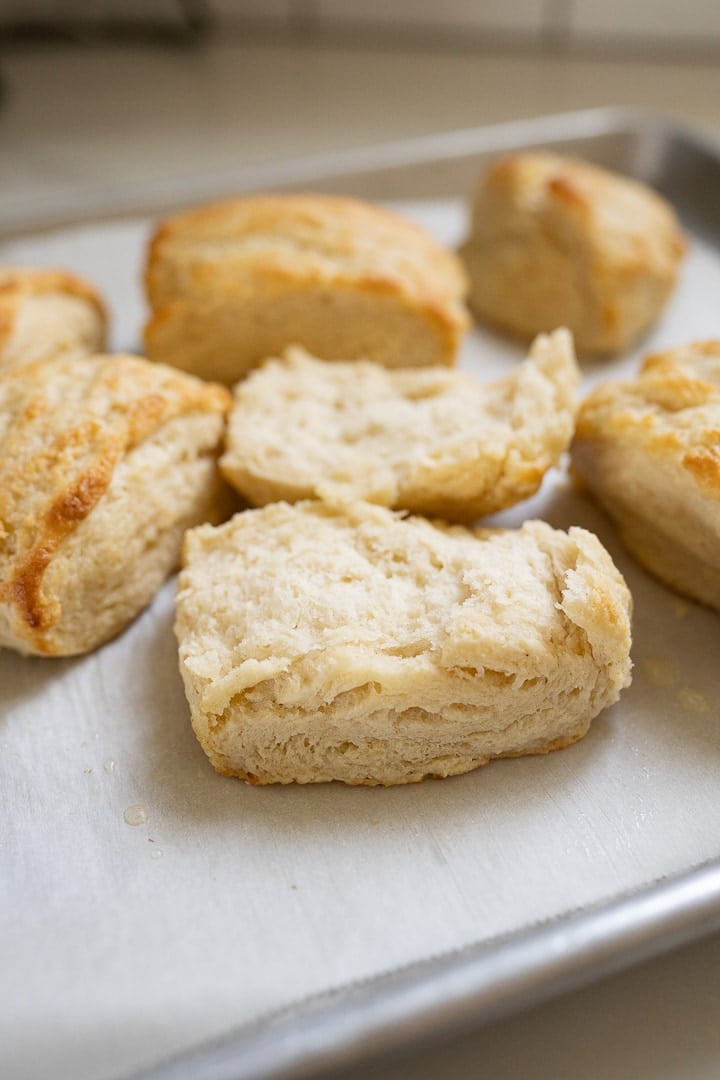 Golden buttermilk biscuits cut in half on a baking sheet. 