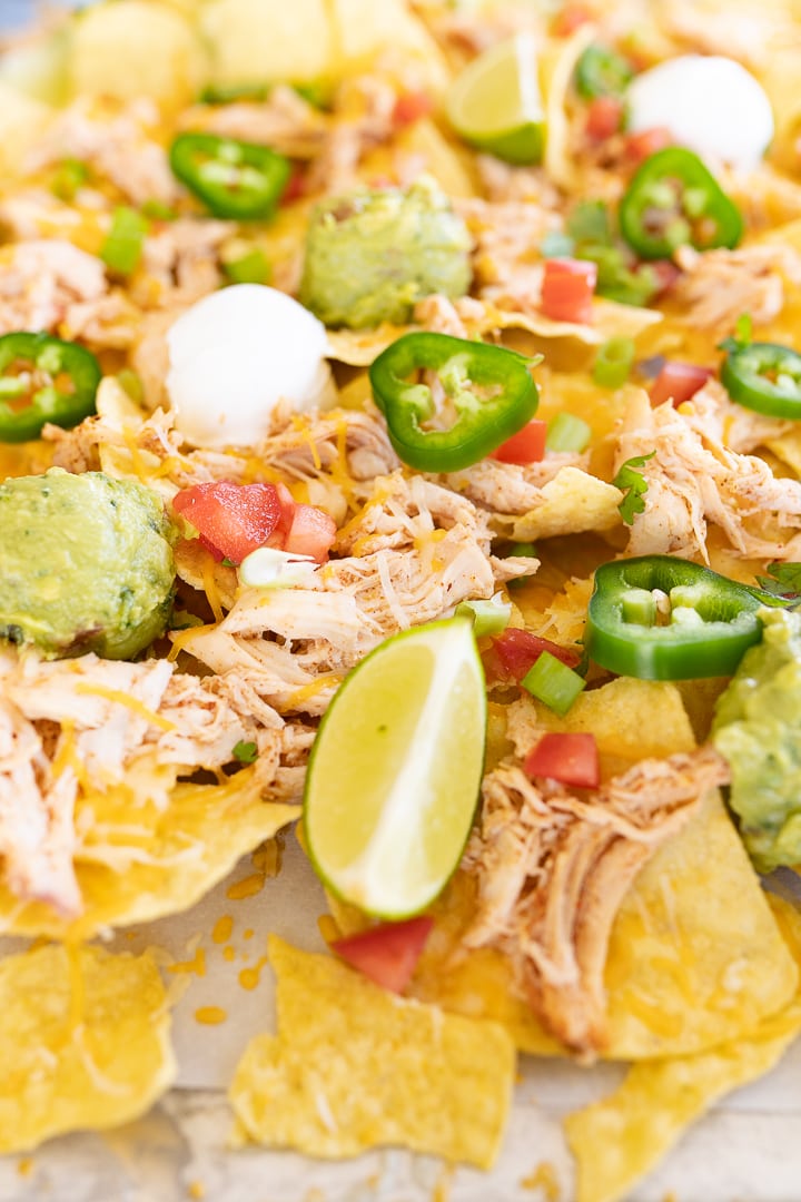 Close up of chicken nachos topped with various toppings. 