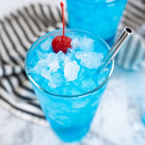 Aerial view of a glass of blue sonic ocean water, topped with a marashcino cherry and served over pebble ice.