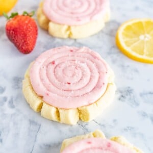 strawberry lemonade cookies on the counter next to lemon slices and strawberries.