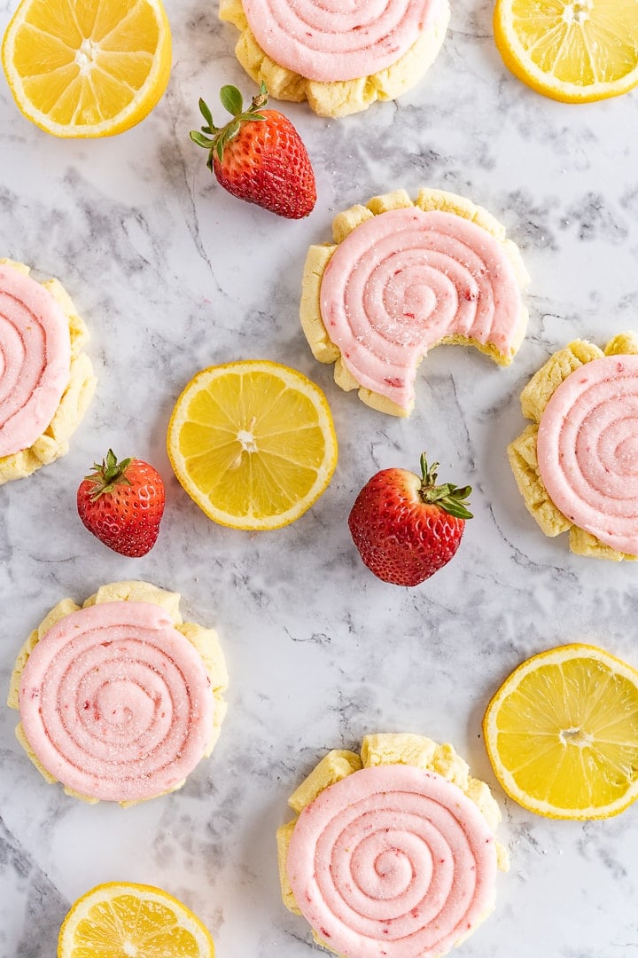 strawberry lemonade cookies on the counter next to some lemon slices and some strawberries. 