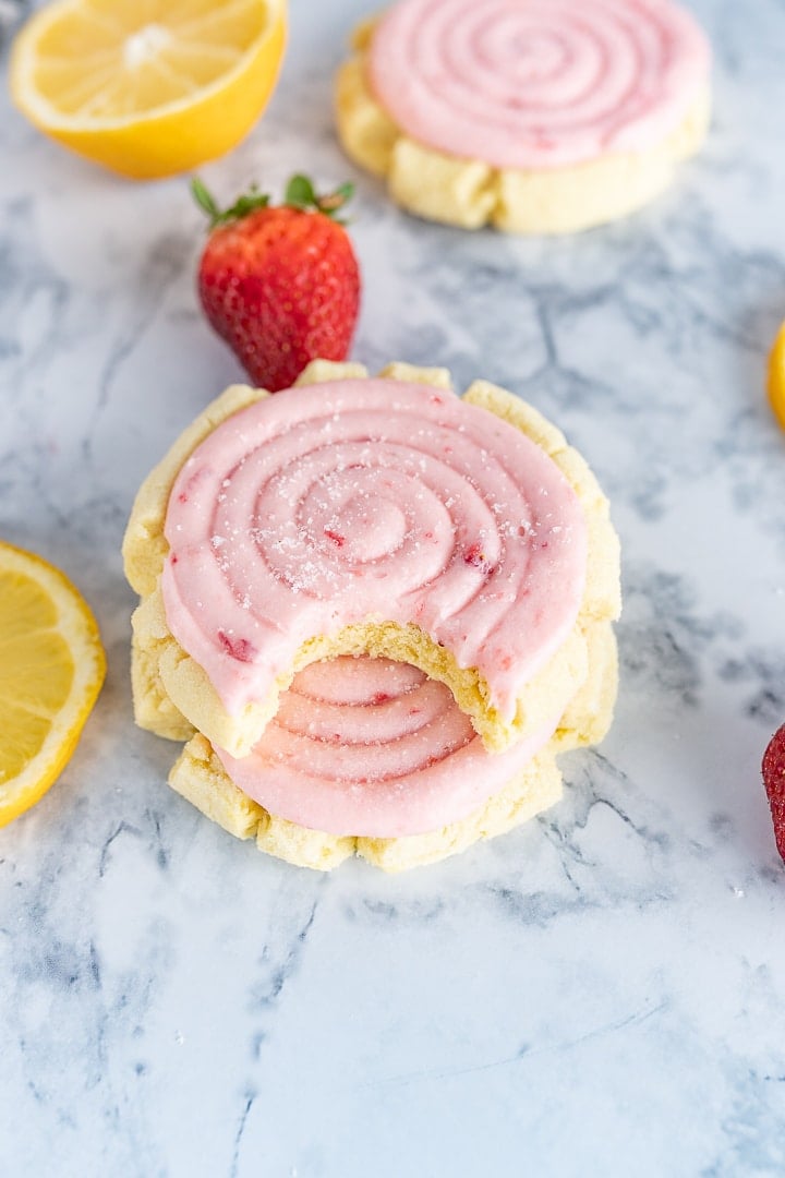 strawberry lemonade cookies, on the counter next to some lemons and strawberries. 