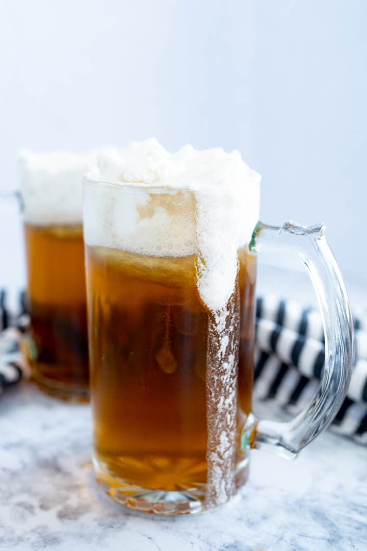 Two chilled mugs of butterbeer topped with foam.
