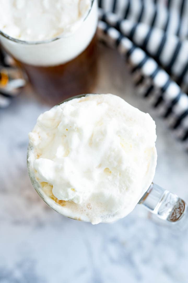 Aerial view of a glass of butterbeer topped with butterscotch foam. 