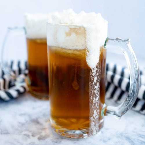Two chilled mugs of butterbeer topped with foam.