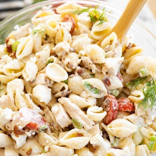 Aerial view of a bowl of chicken bacon ranch pasta salad with a wooden spoon sticking out of it.