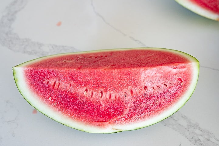 Steps how to cut a watermelon: Cut in half again length wise.