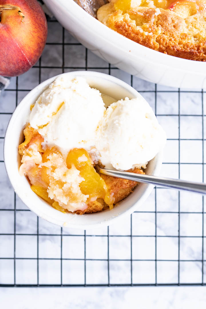 Aerial view of a bowl of homemade peach cobbler with ice cream. 