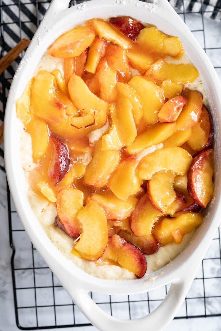 Easy peach cobbler arranged in a baking dish prepared to bake. 