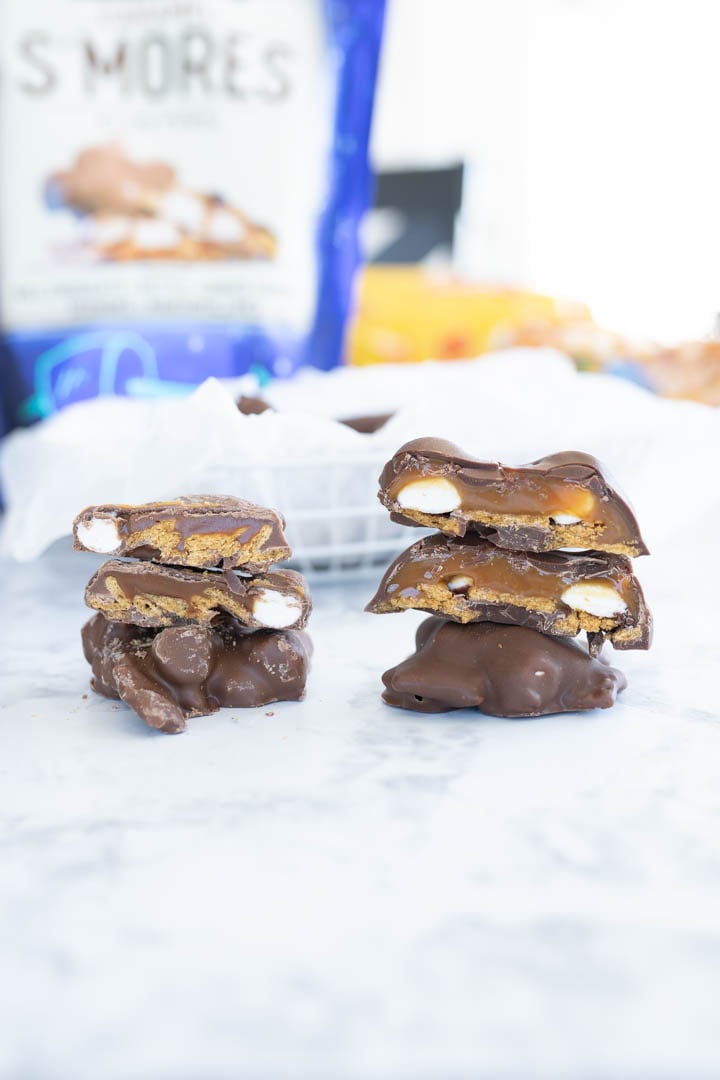 S'mores clusters cut in half and stacked next to each other. Behind the clusters is a bag of the costco s'mores mix. 