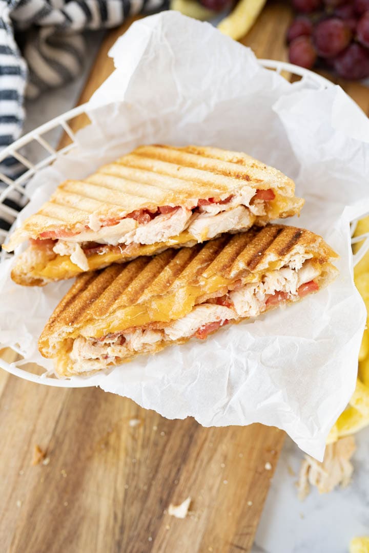 A grilled chicken panini cut in half with the open side facing up.