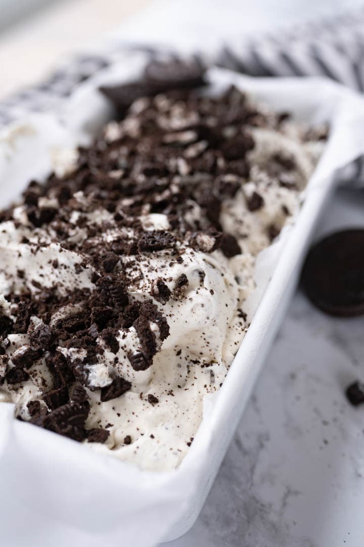 A bread pan with frozen homemade oreo ice cream in it. 