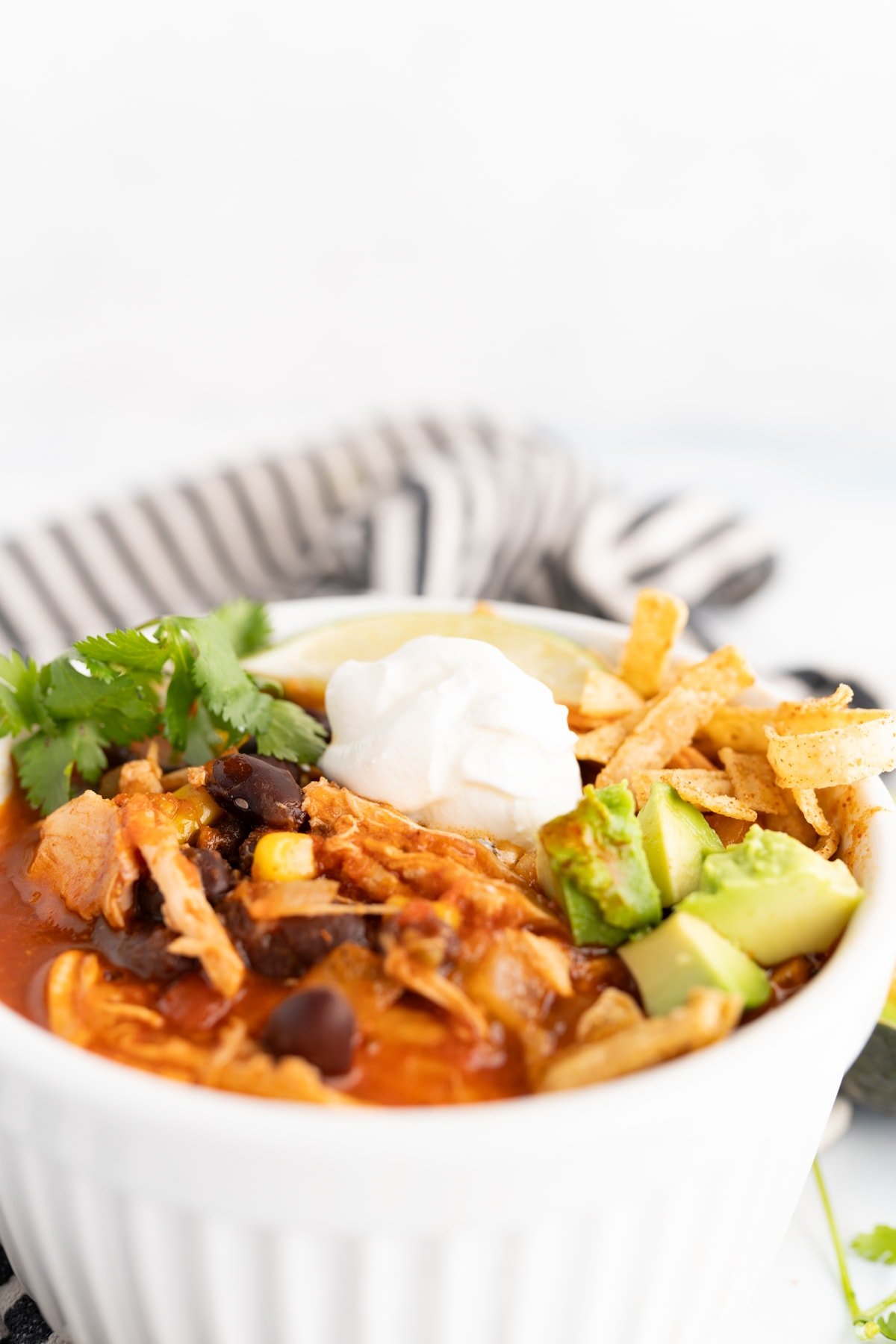 Close up of toppings on top of a bowl of easy chicken tortilla soup. 