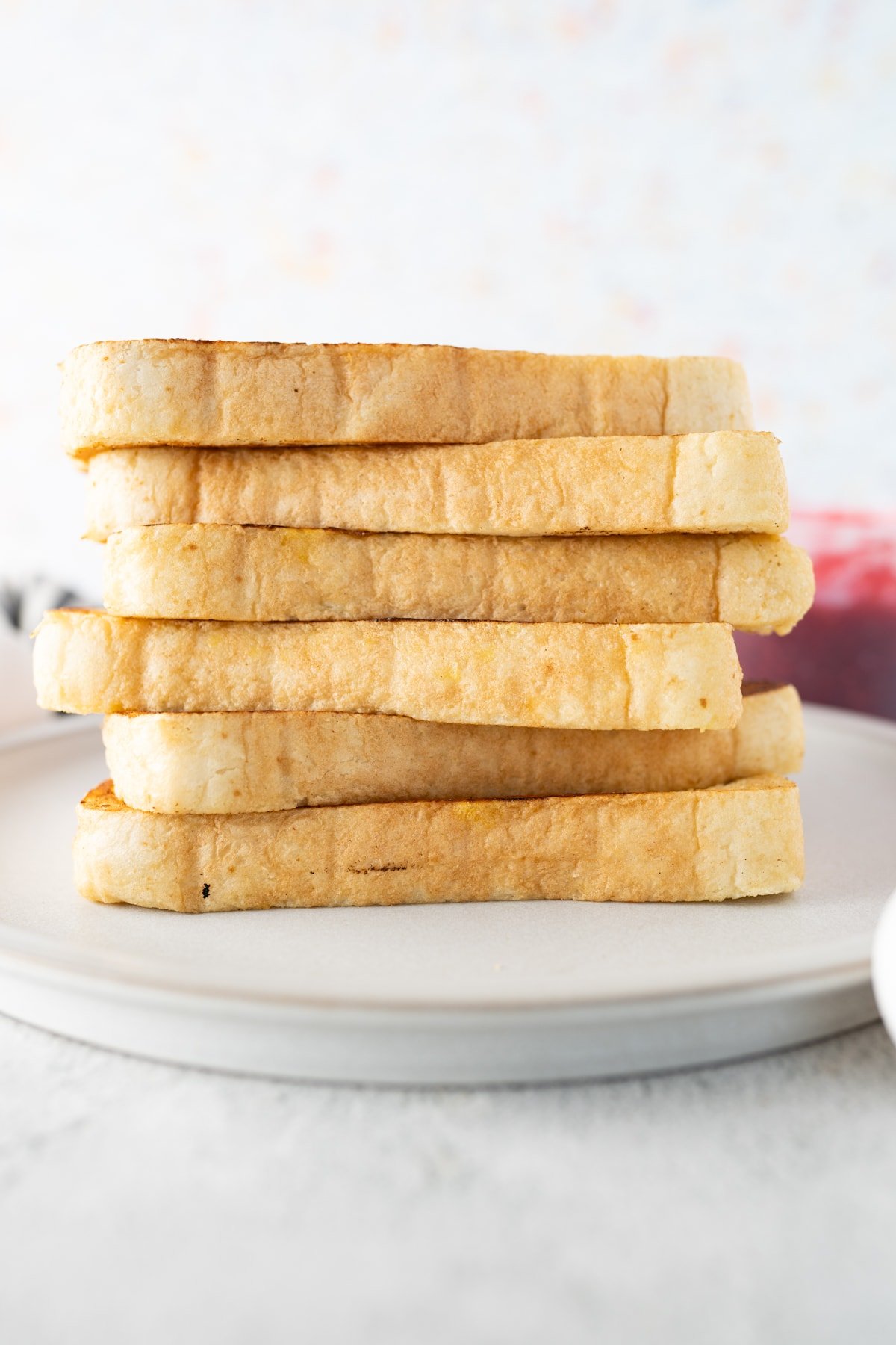 A stack of french toast on a plate, stacked high. 