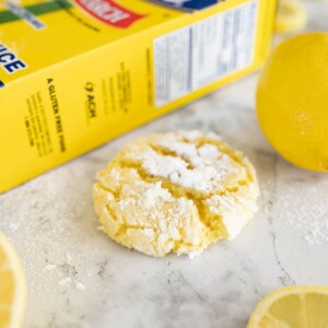 lemon crinkle cookie on the counter next to a lemon and a yellow box of Argo corn starch.