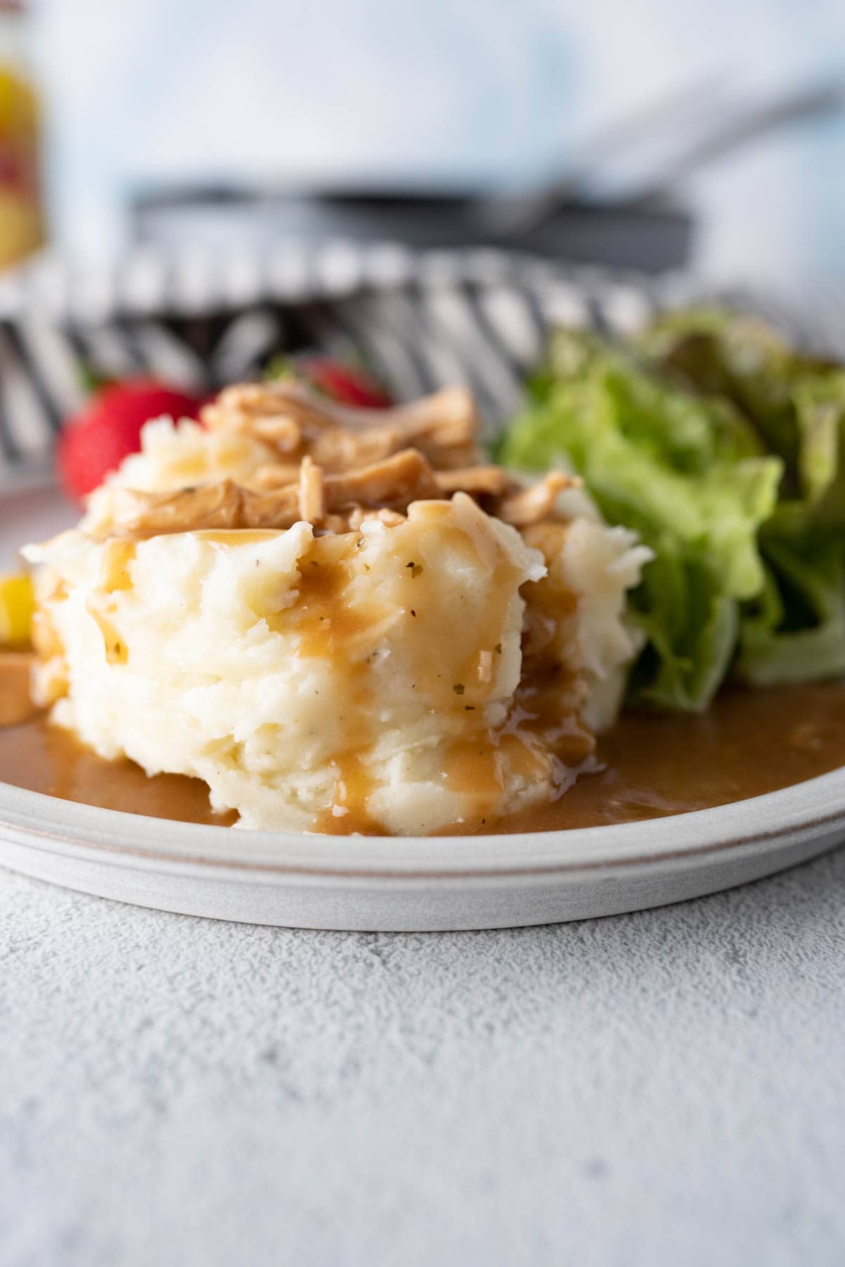 Side view of mashed potatoes topped with mississippi chicken. 