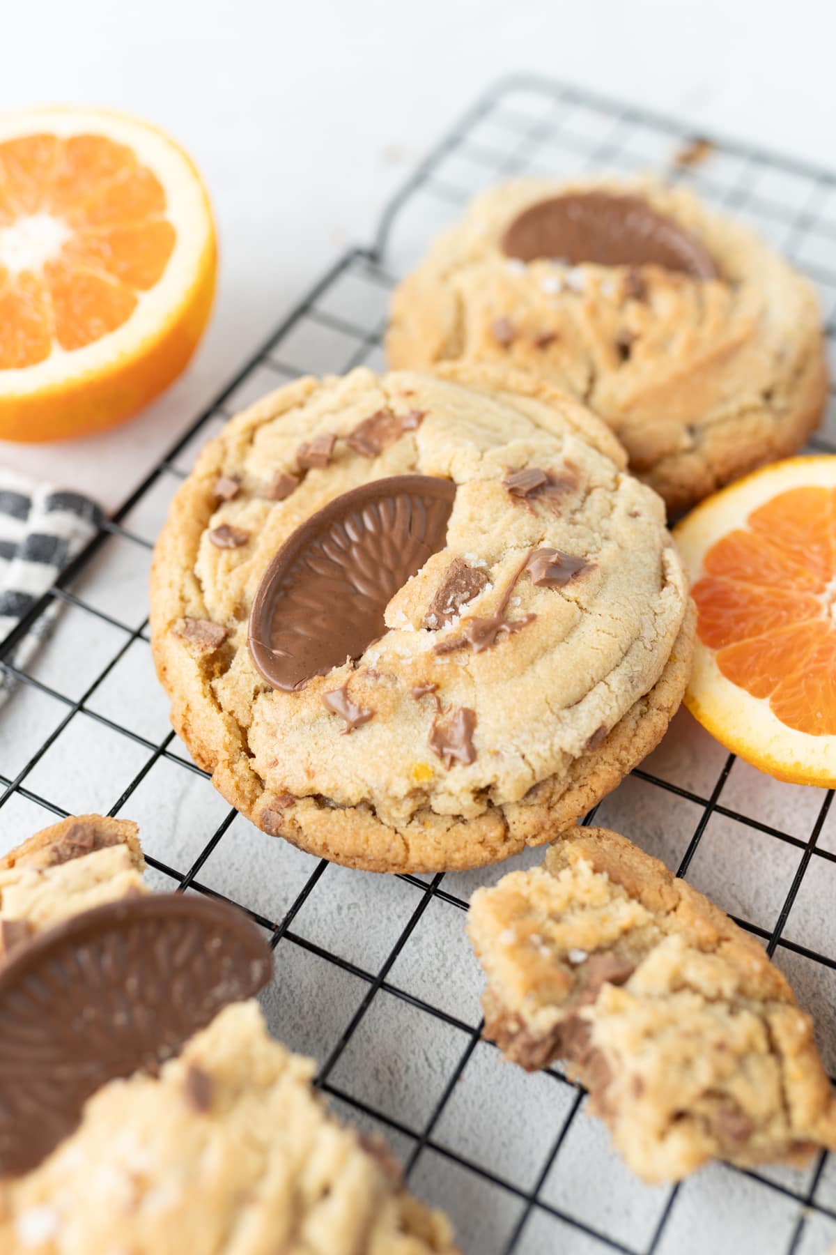 Image of chocolate orange cookies on a wire cooling rack with orange slices and chocolate orange slices. 
