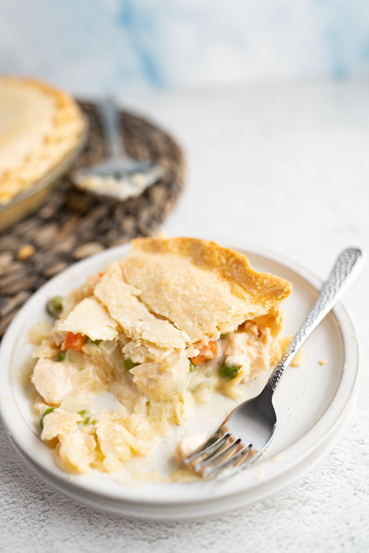 A slice of chicken pot pie on a plate with a fork. 