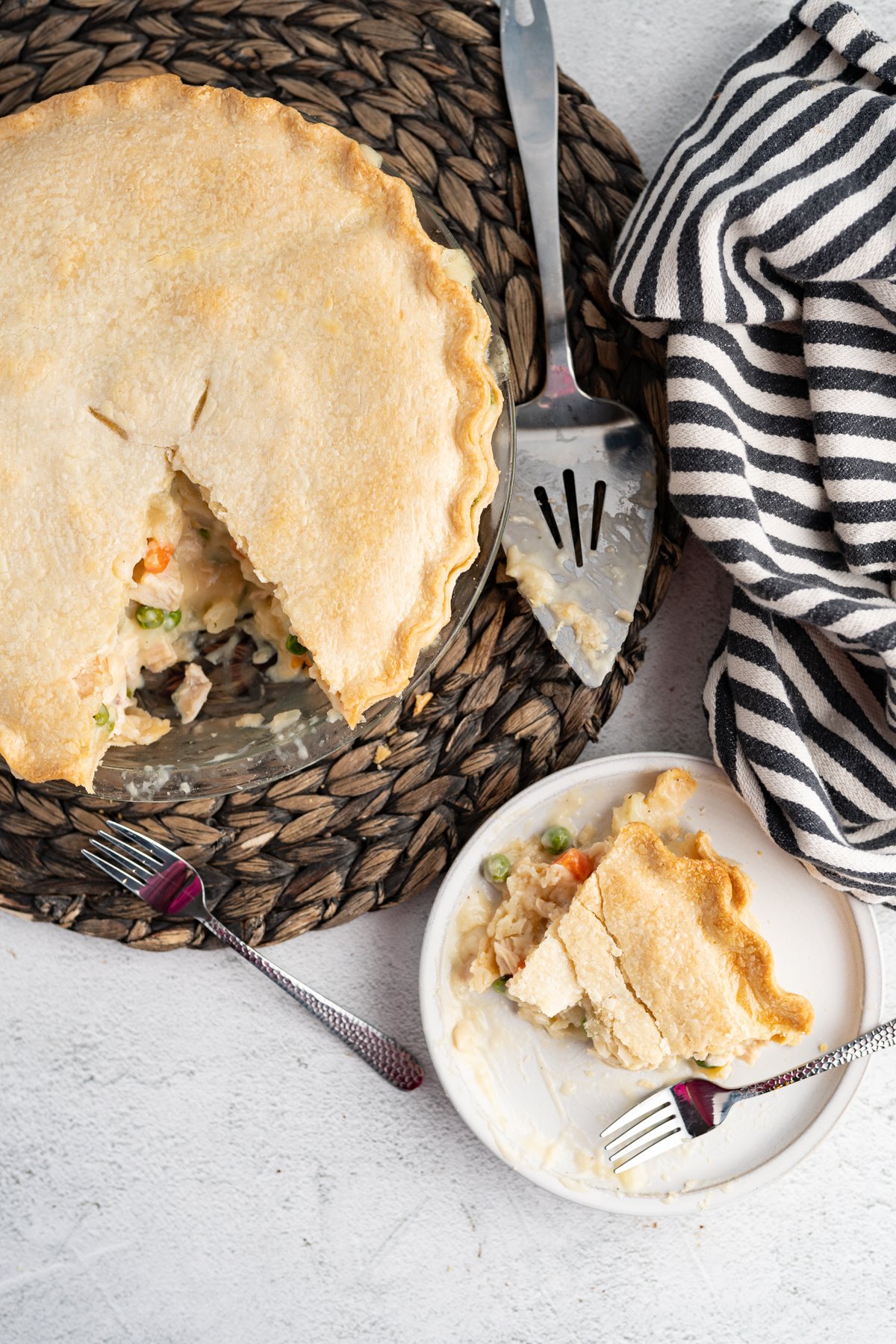 Aerial image of a whole easy chicken pot pie with a slice cut out of it and served on a plate next to it. 