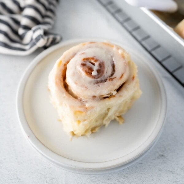 An image of a single frosted cinnamon roll on a plate.