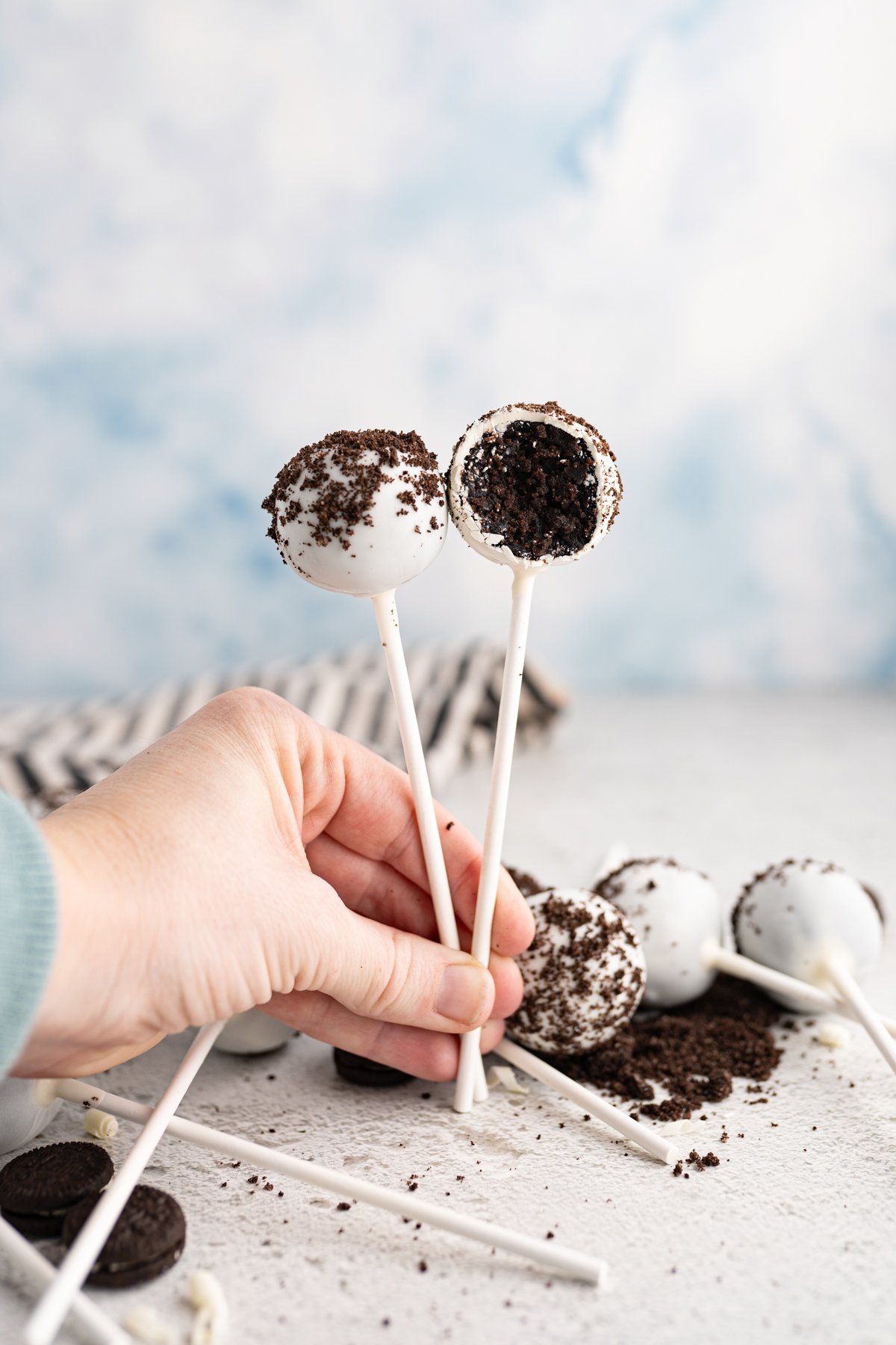 A hand holding two cookies and cream cake pops. 
