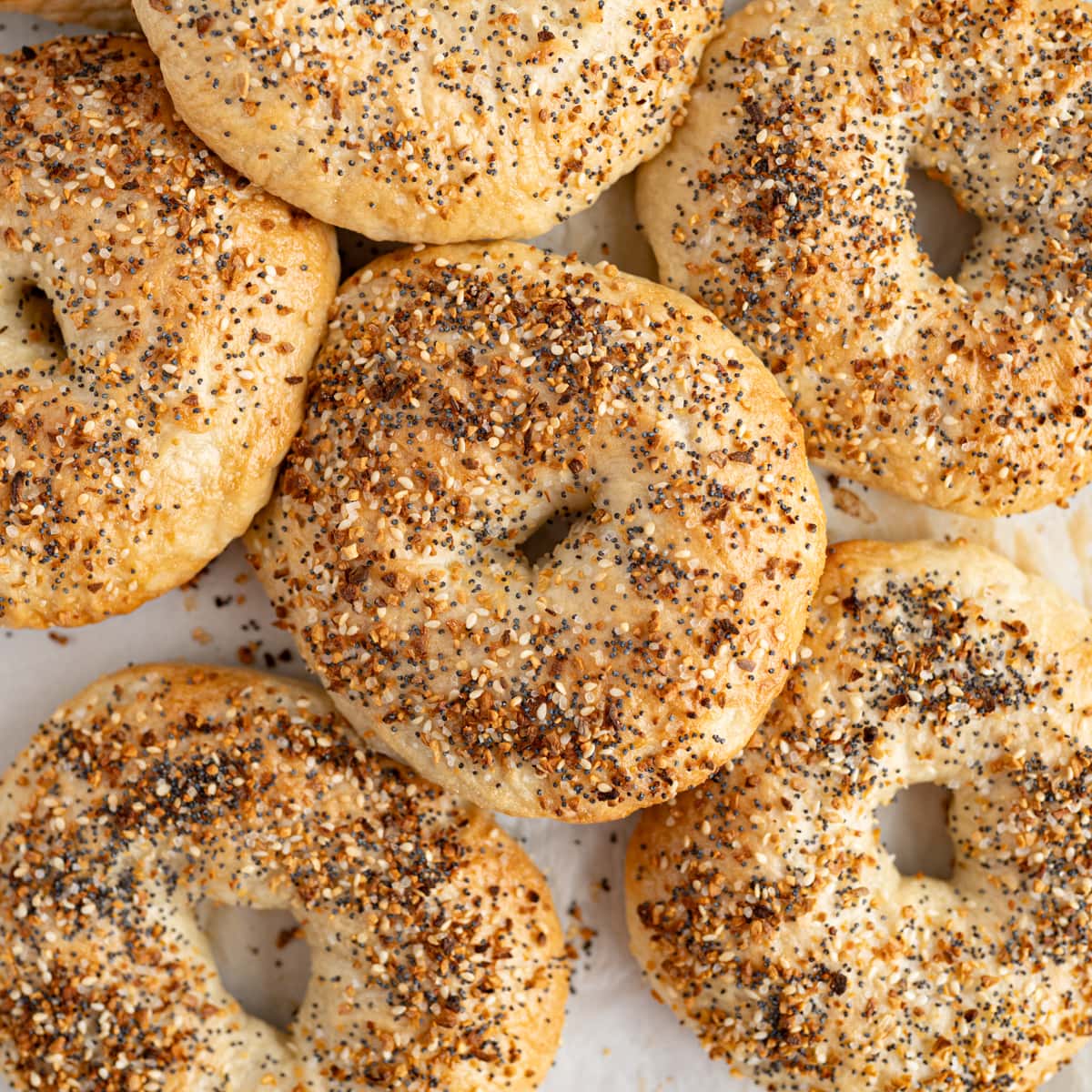 A pile of everything bagels on the counter. 