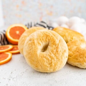 Image of a plain bagel propped up by an orange.