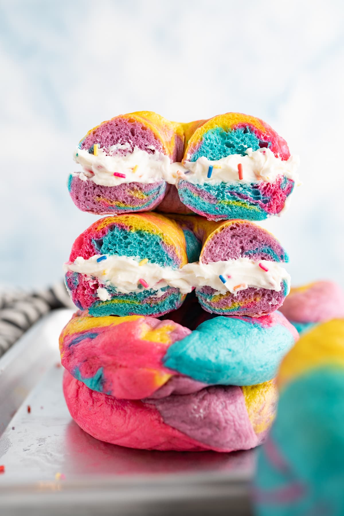 Rainbow bagels with cream cheese stacked on top of each other. 