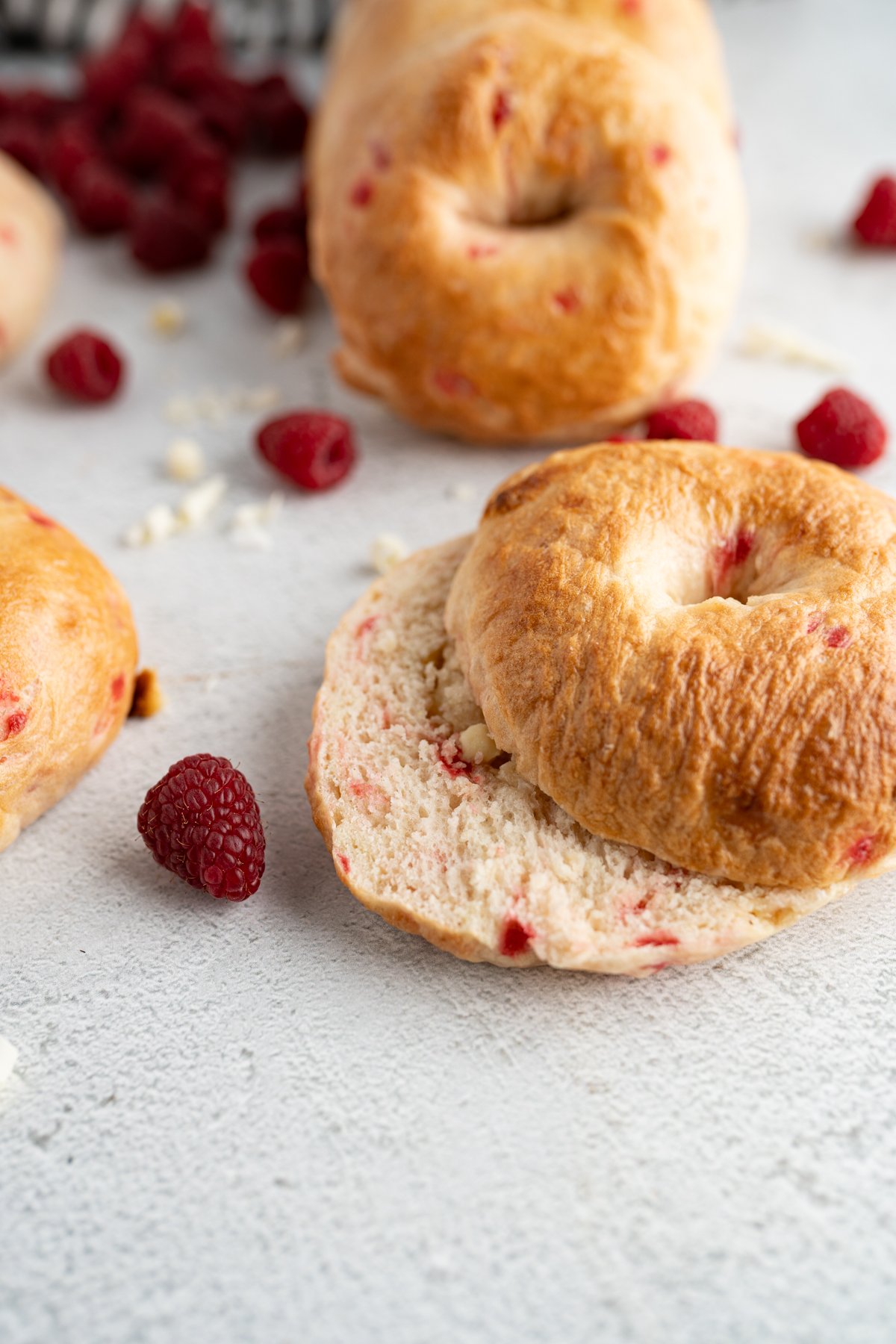A raspberries and cream bagel cut in half on the counter. 