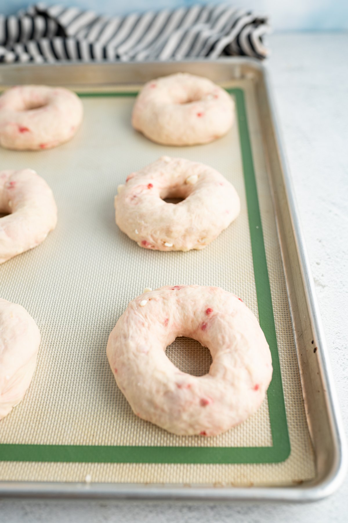Raspberry bagels that have risen on a tray. 