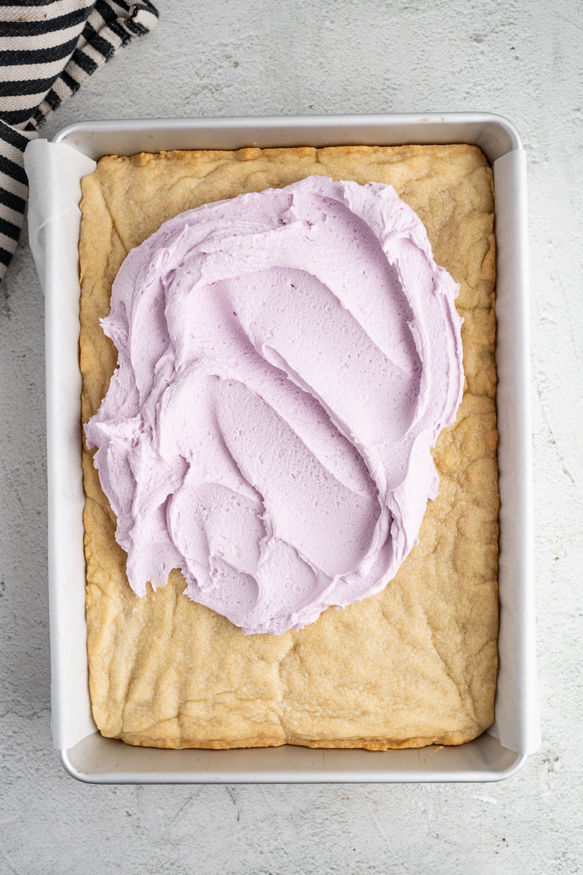 Baked sugar cookie bars partially topped with purple frosting. 