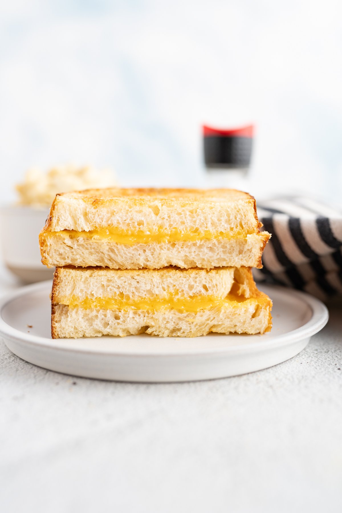 An air fryer grilled cheese cut in half and stacked on each other on a plate. 