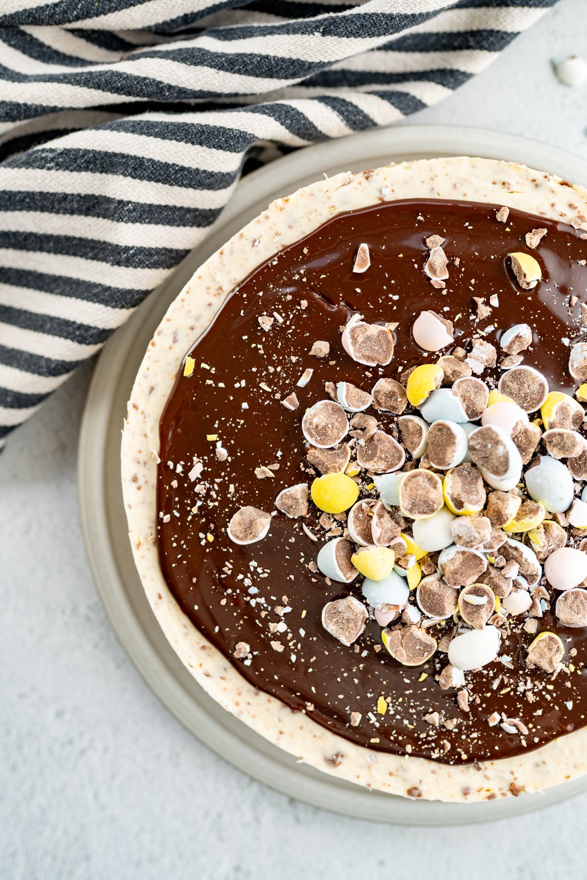 Aerial view of a cadbury egg cheesecake topped with fudge and more cadbury mini eggs. 