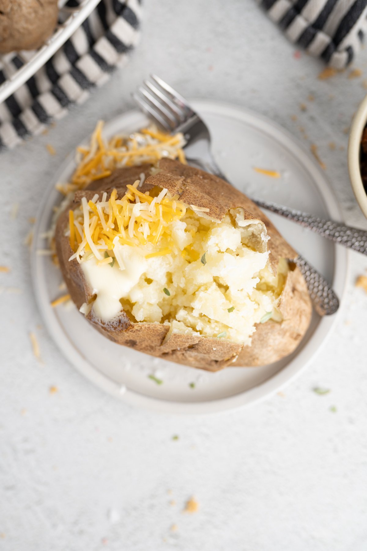 A microwave baked potato with butter and cheese on top. 