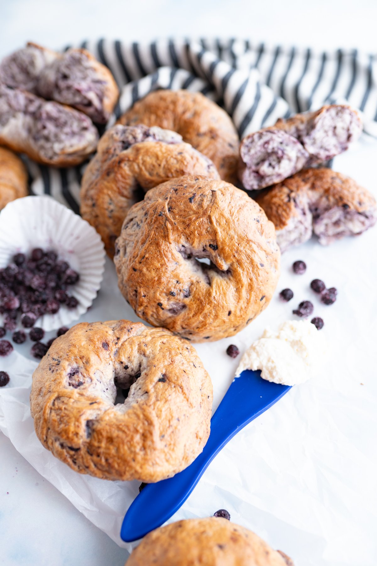A counter full of blueberry bagels scattered. 