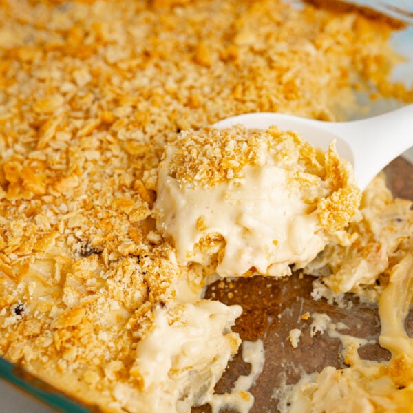 Close up of a serving spoon scooping out funeral potatoes.