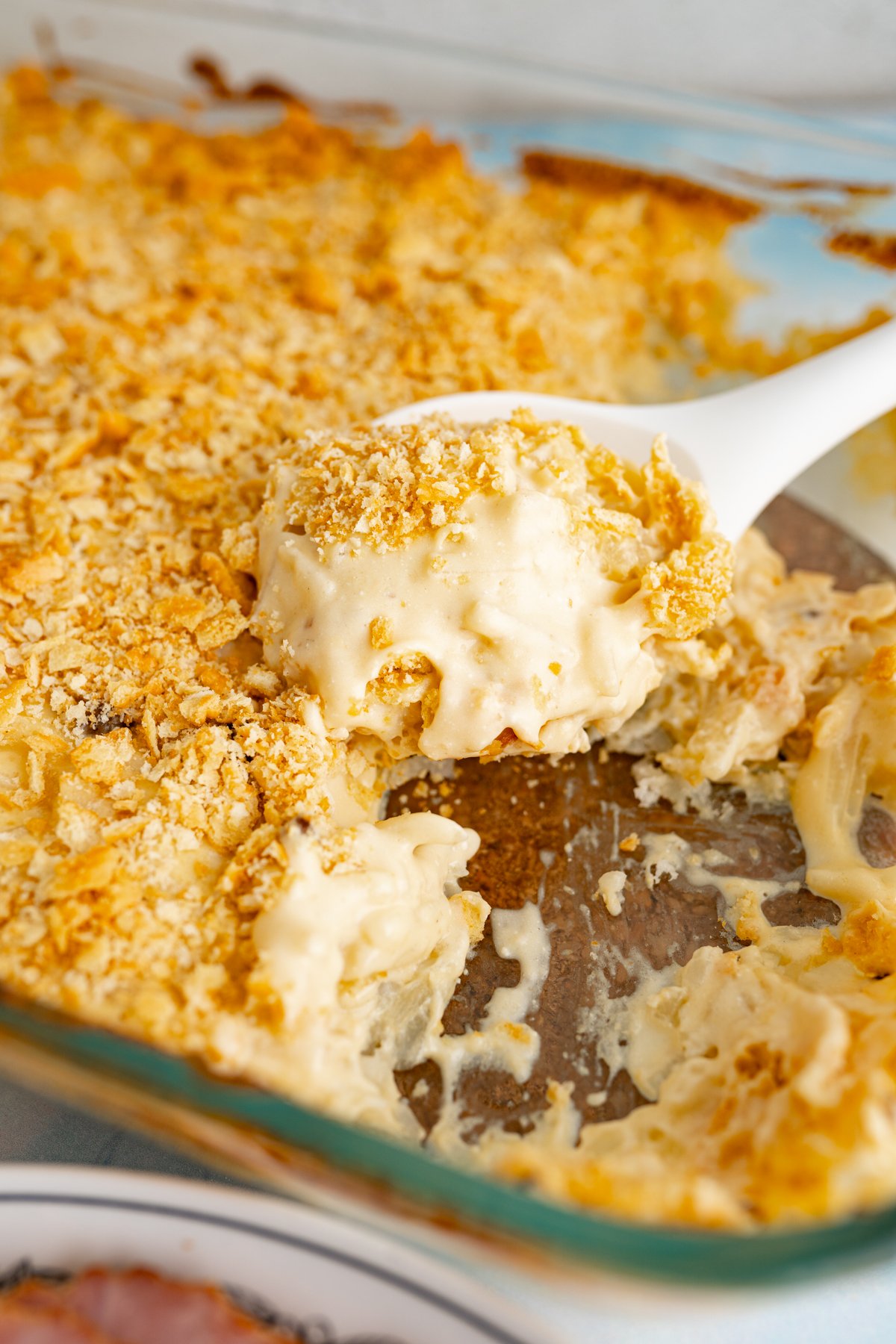 Close up of a serving spoon scooping out funeral potatoes. 