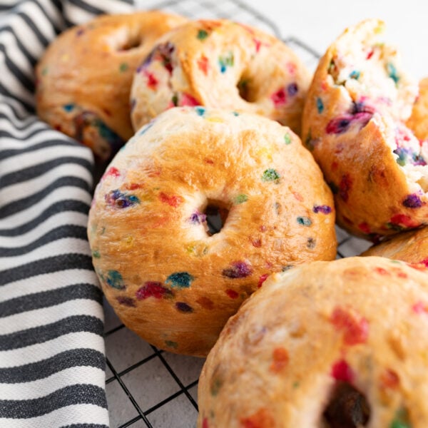 A pile of funfetti bagels on a wire cooling rack.