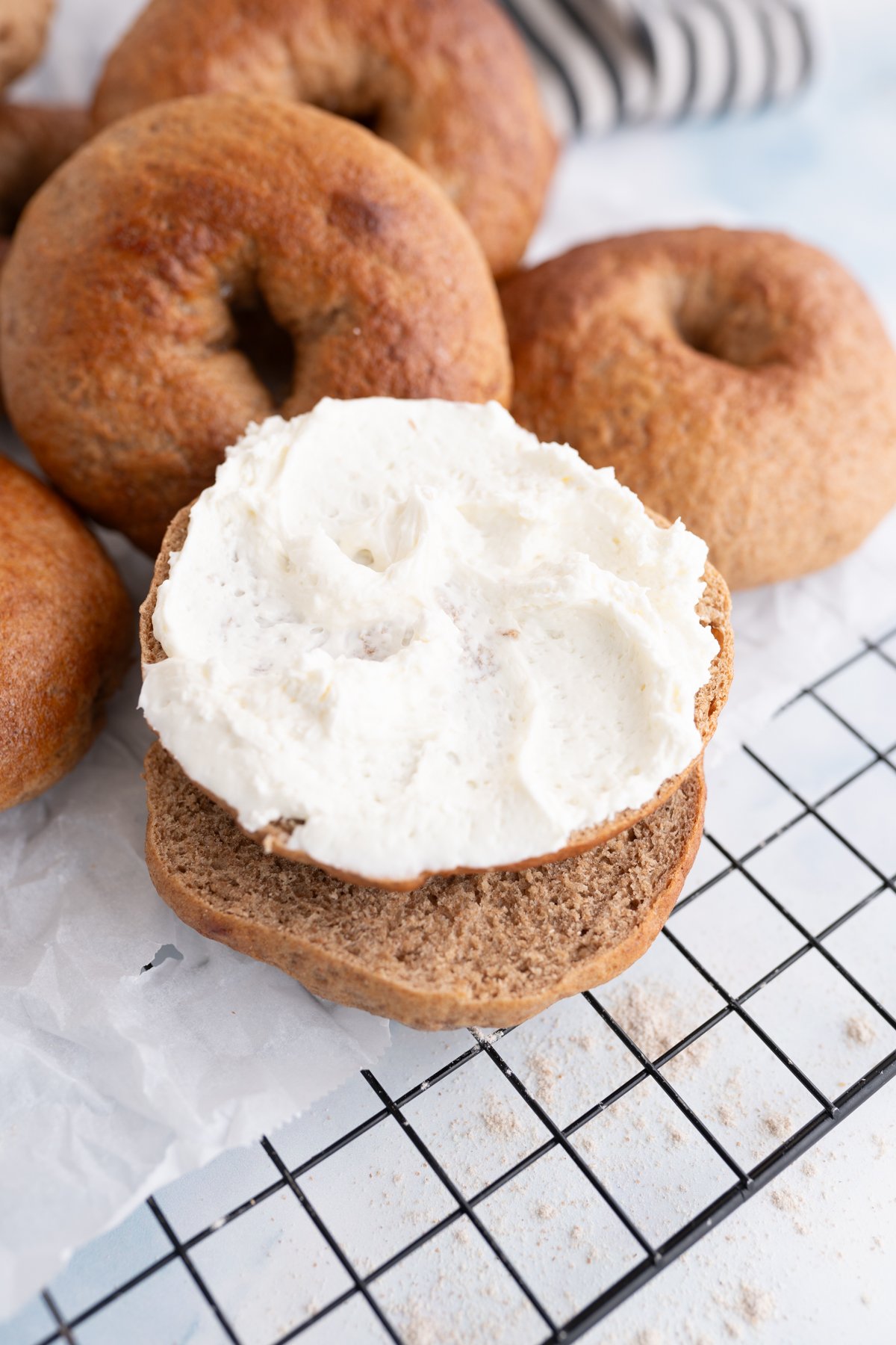 Close up of one whole wheat bagel cut in half and topped with cream cheese. 