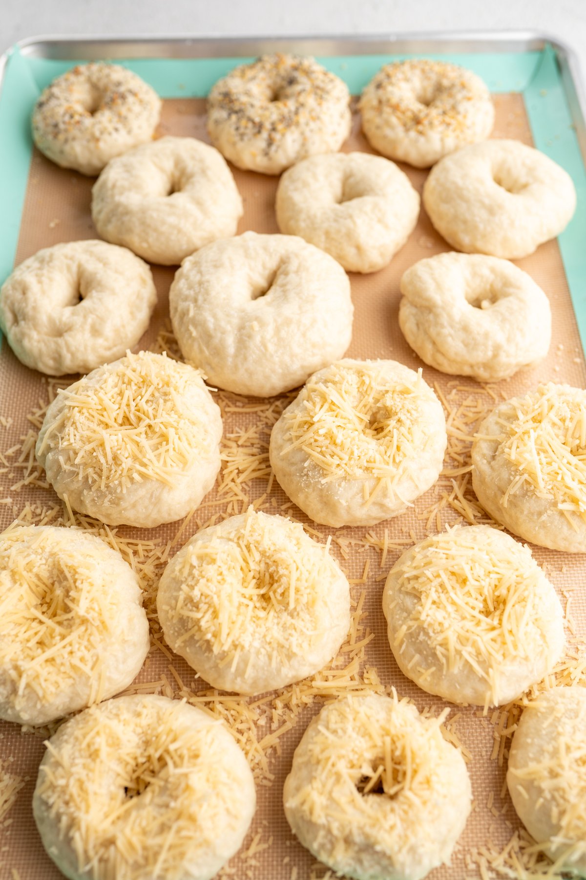 Homemade mini bagels topped with various topping prior to being baked. 