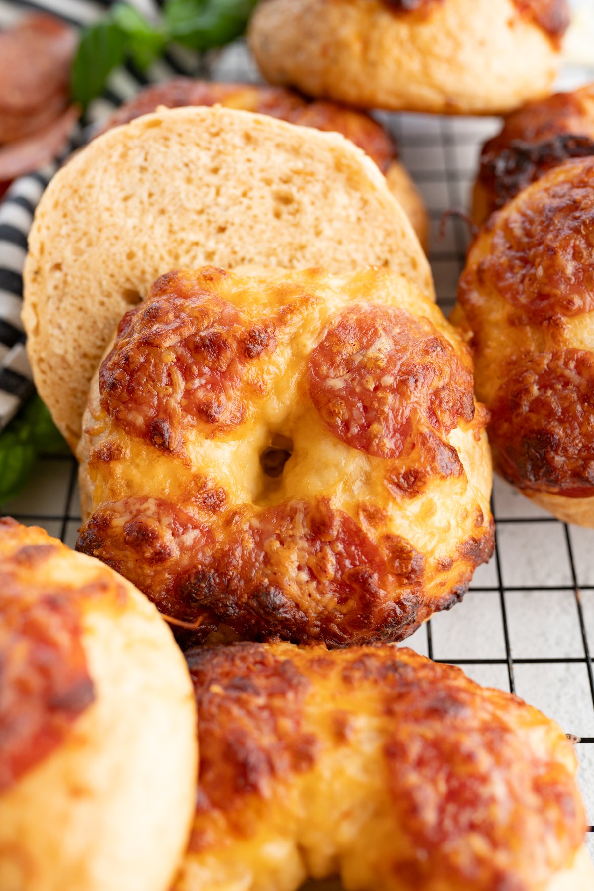 Close up of a pizza bagel cut in half in a pile of additional homemade bagels.