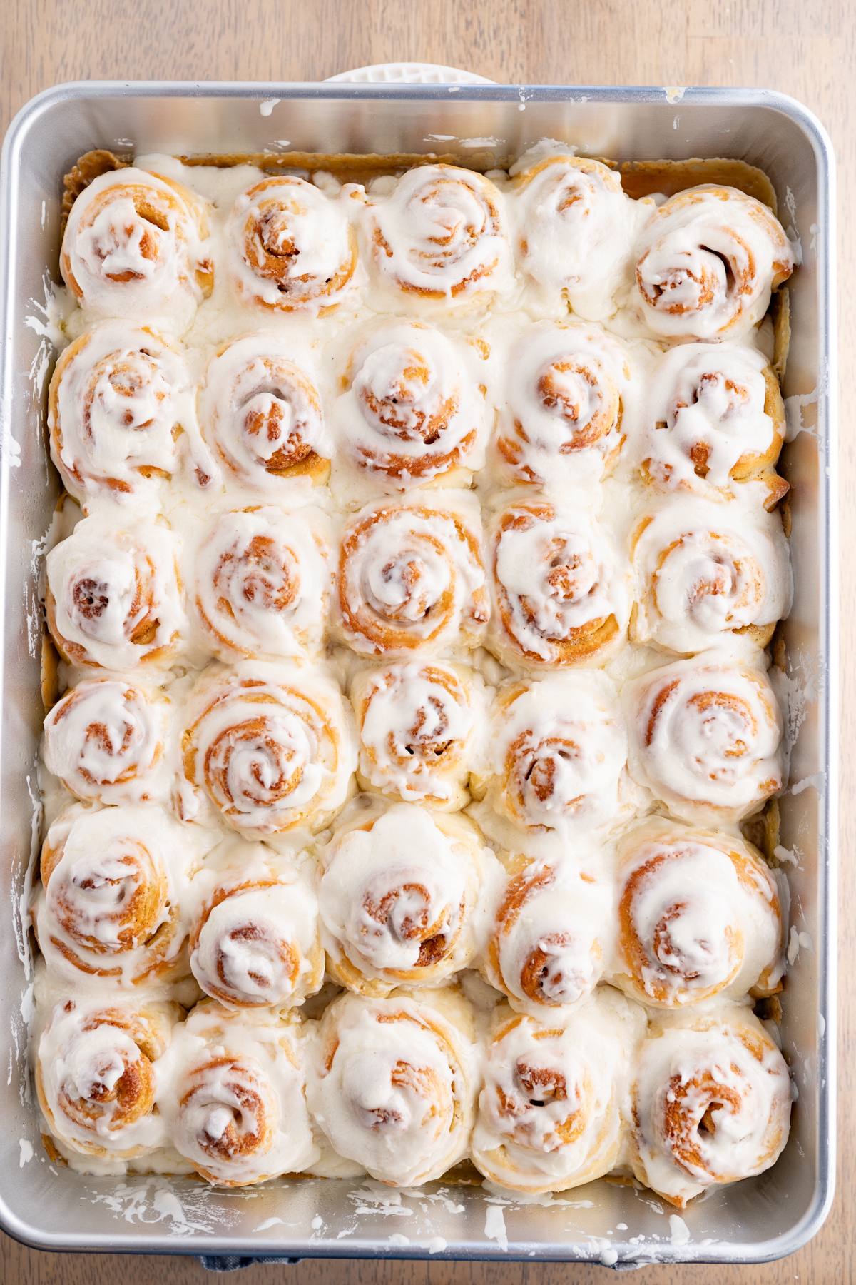 A pan of baked mini cinnamon rolls after being frosted with cinnamon roll icing.